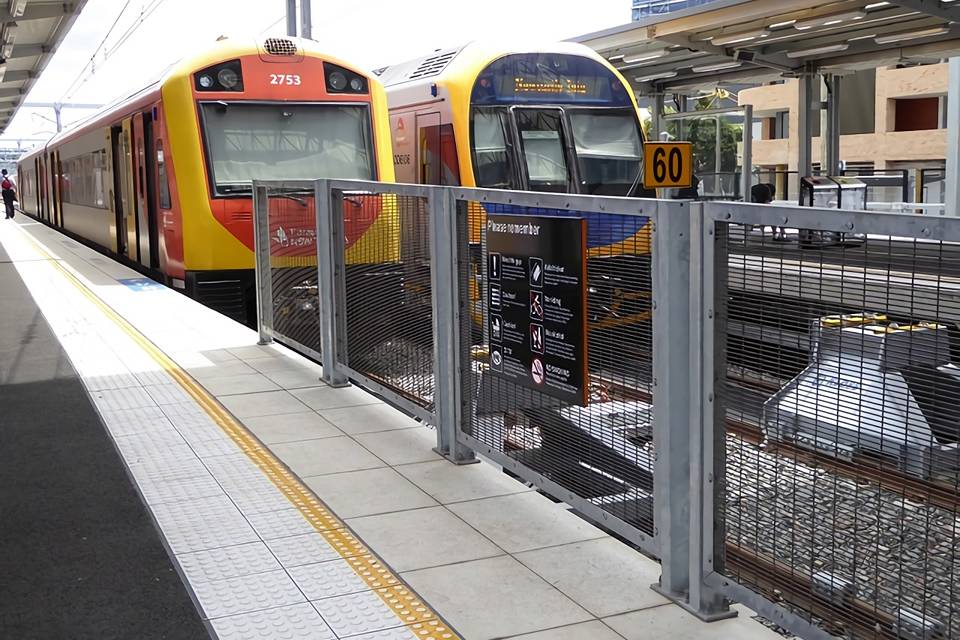 Two trains are stopped along the railway tracks surrounded by 358 security fence.