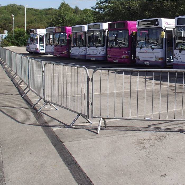 Crowd control barriers are used to set up a temporary parking lot for buses.