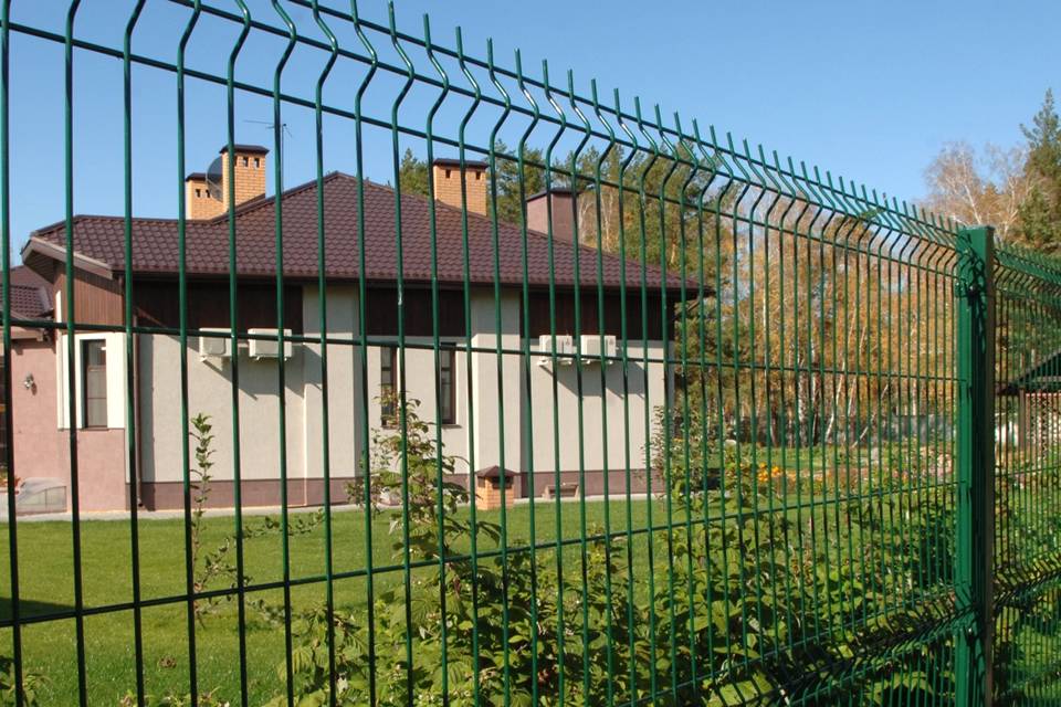 Many plants are planted in the house yard encircled by curvy welded fence.